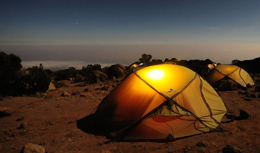a photo of a campsite at sunset with two tents and a view of the dusk sky